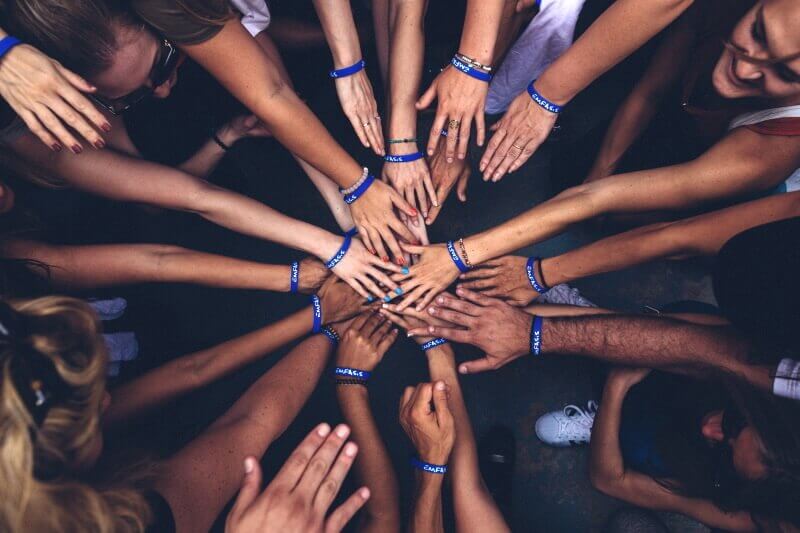 Multi-ethnic group of people standing in a circle touching hands in the middle